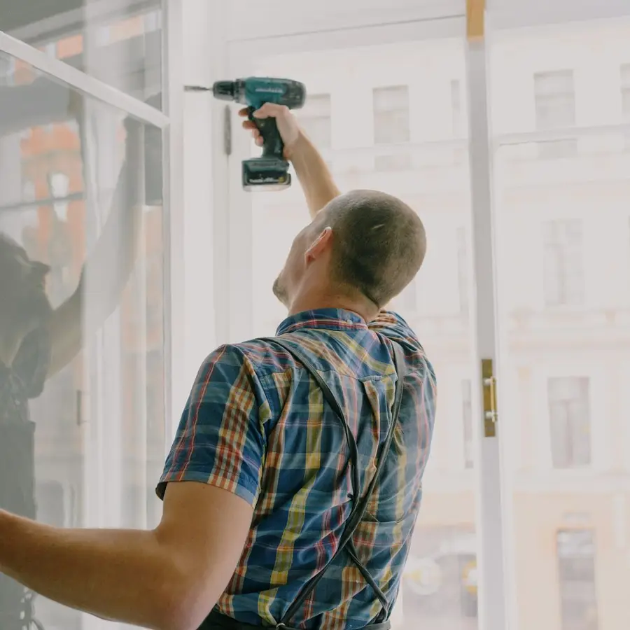 Window fitter drilling a new frame into place