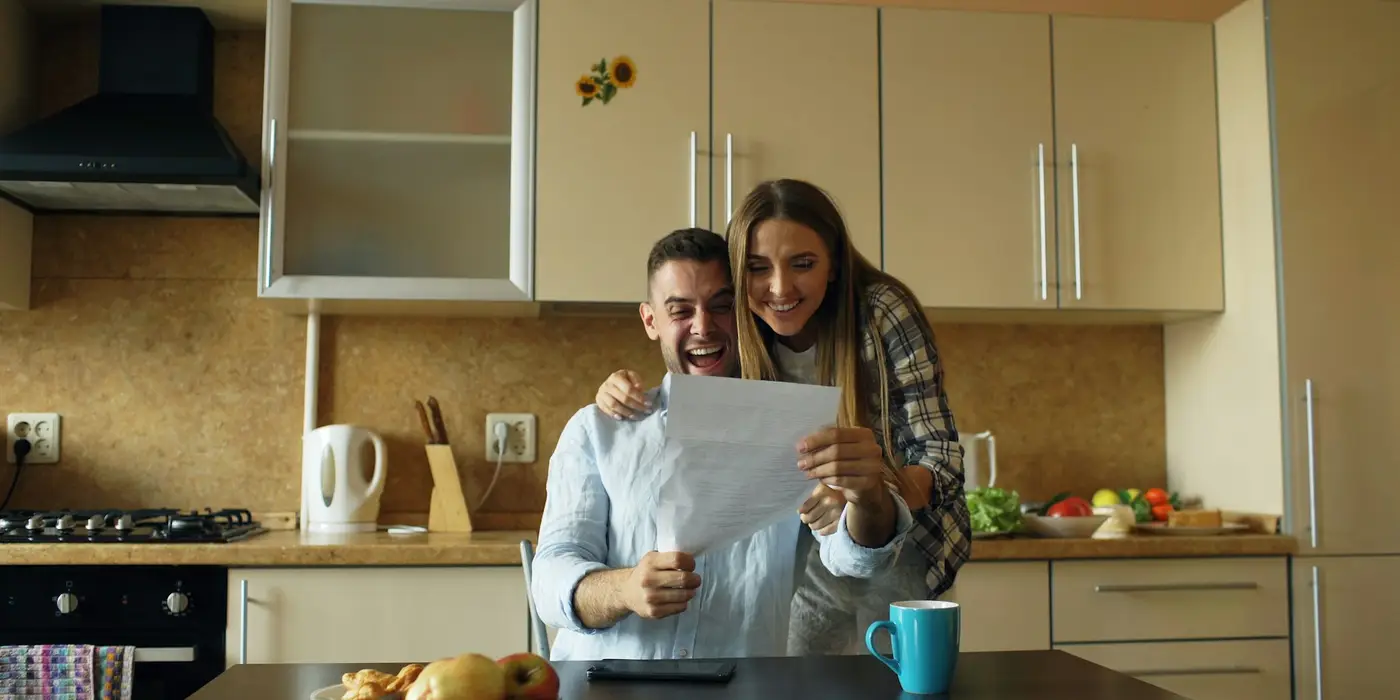 Couple at their kitchen table reading through a letter together