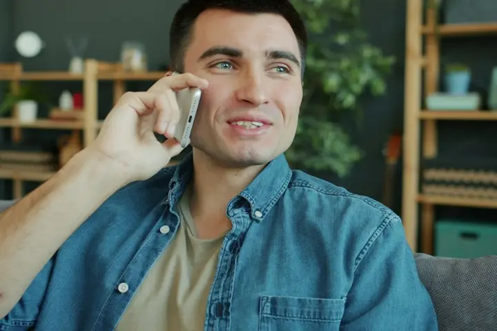 Smiling man taking a phone call at home